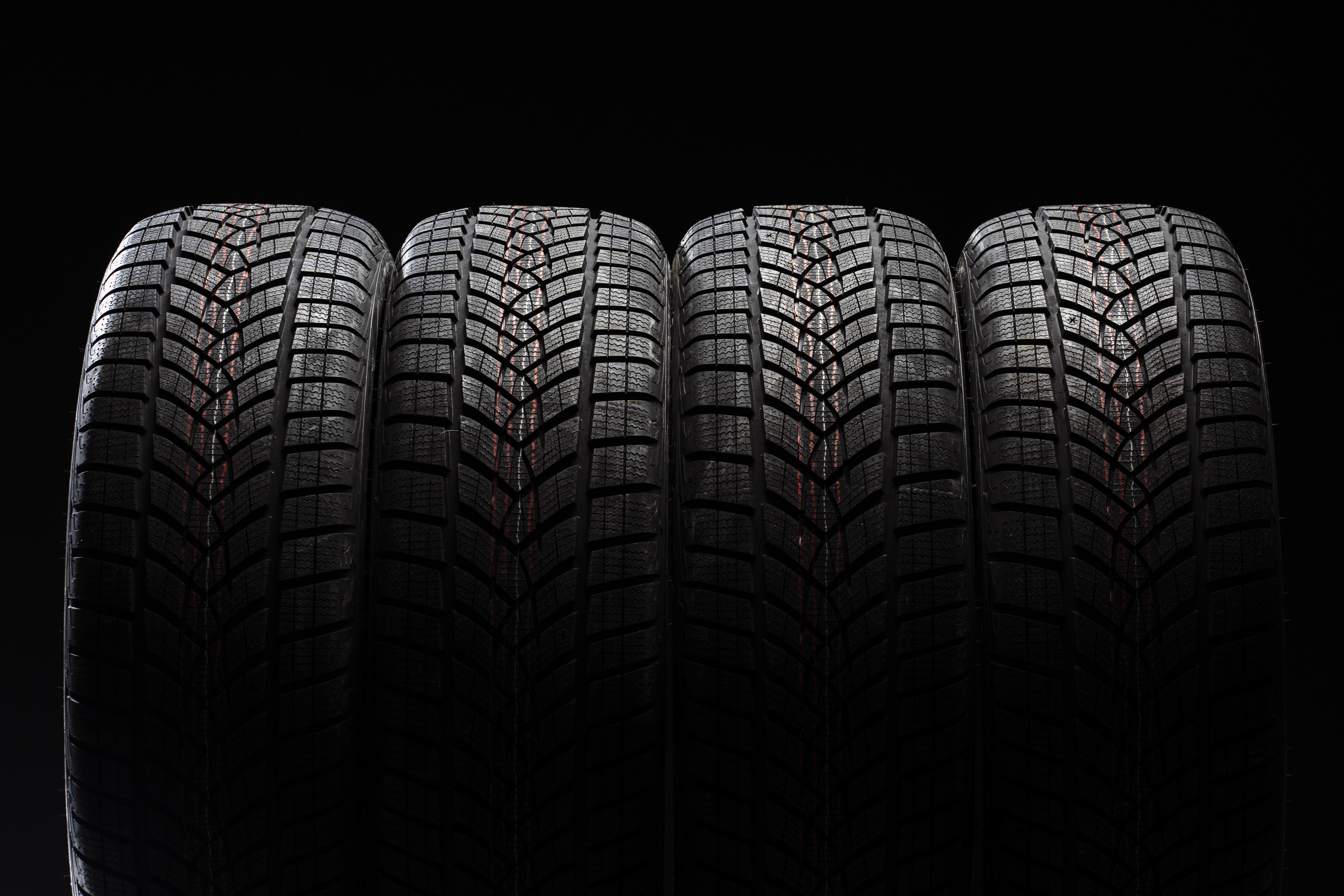 Set of four new tires lined against a dark backdrop